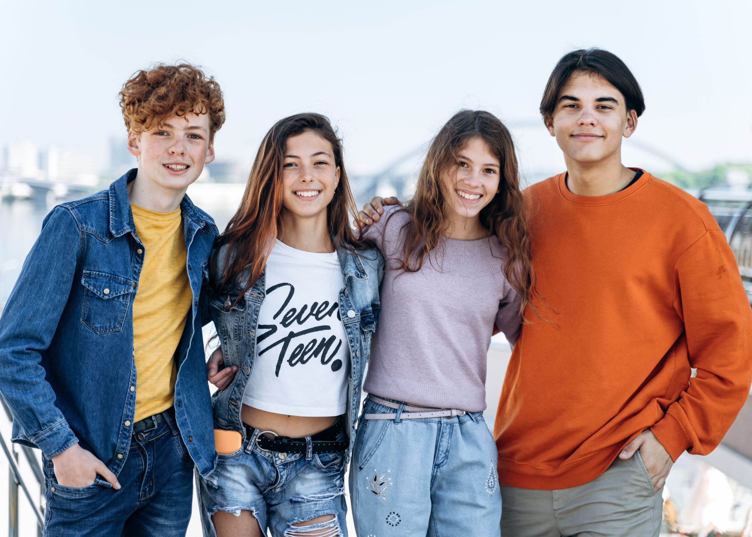 Beautiful, modern, smiling teenagers embracing posing against the backdrop of the city. Positive children - teenagers posing.